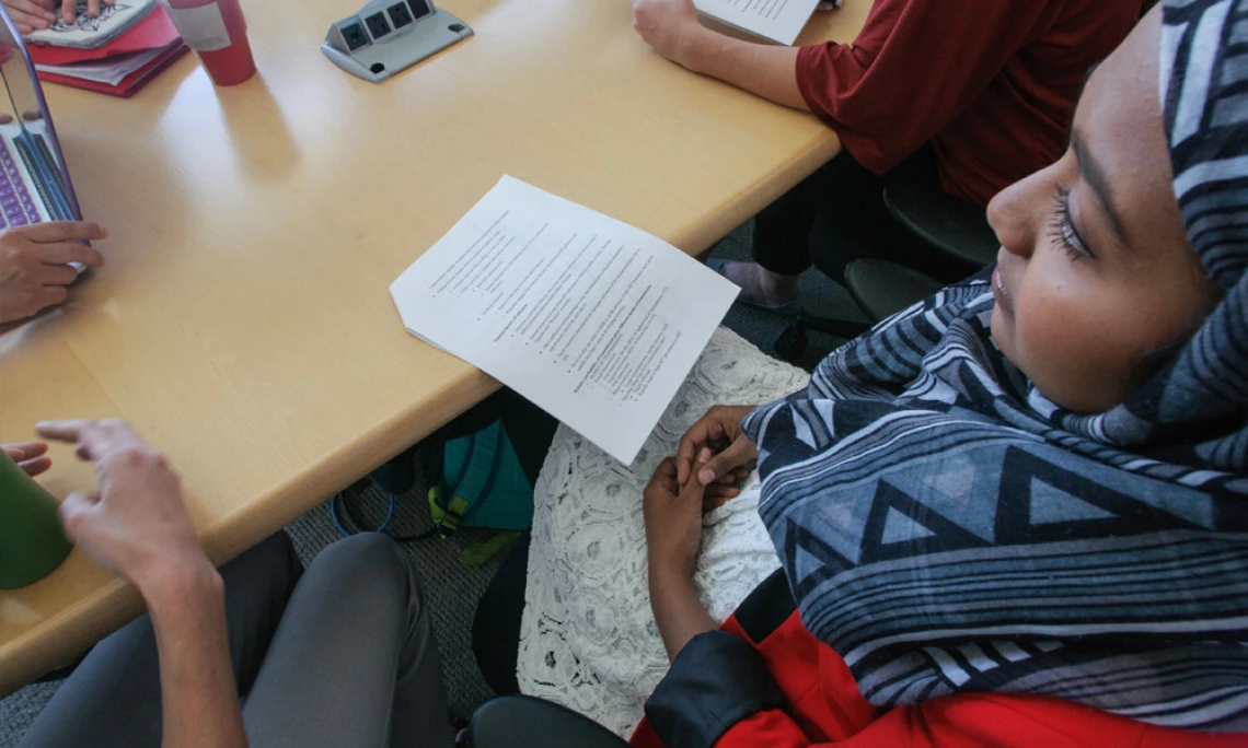 Student with notes seated at class table with other students