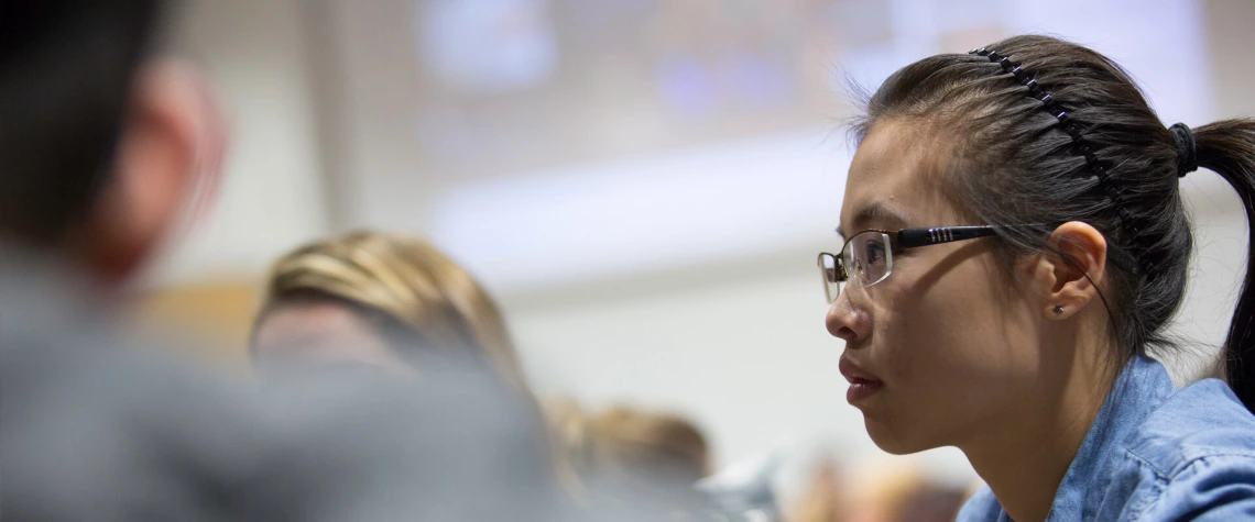 Young woman in classroom listening to lecture