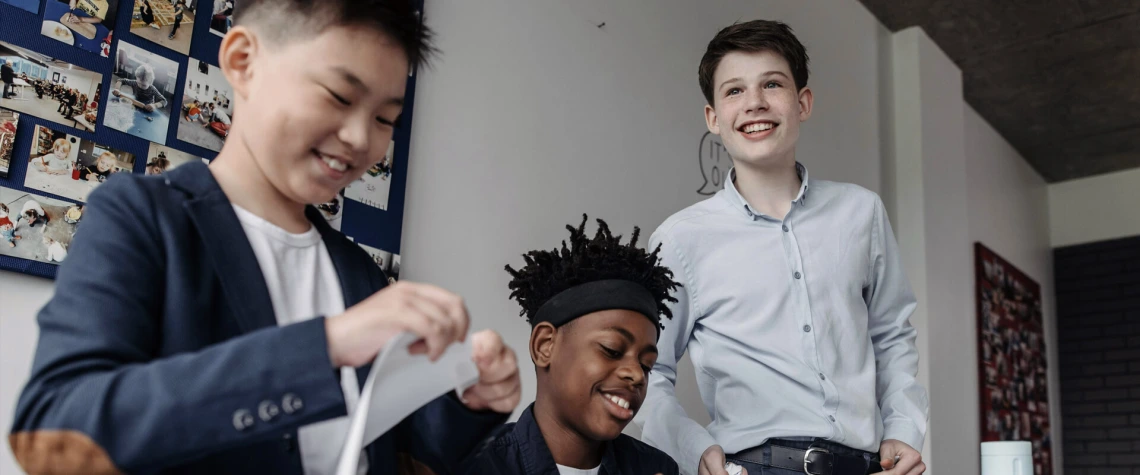 3 young teen boys smiling and working on a project
