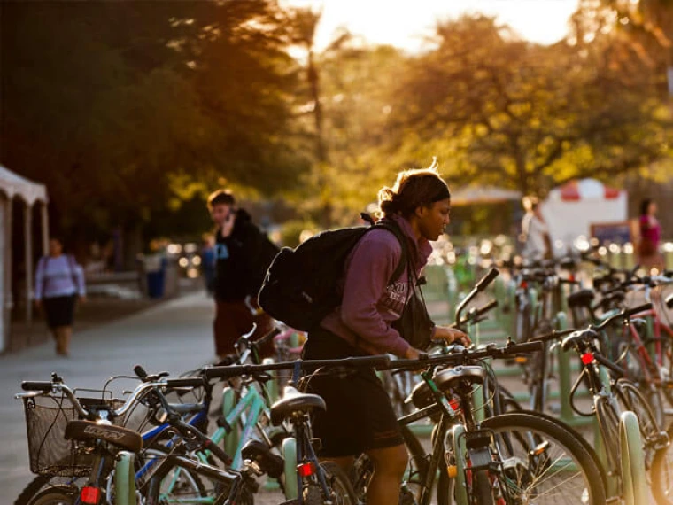 Man putting bike onto bike rack on UA campus